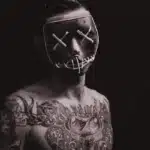 Tattooed man wearing a neon-lit mask – symbolizing stigma, deviance, and identity concealment