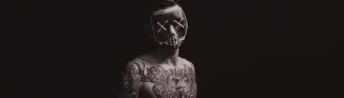 Tattooed man wearing a neon-lit mask – symbolizing stigma, deviance, and identity concealment