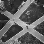 Karriere/ Entwicklung/ Lebenslauf Schwarz-weißes Luftbild einer Person an einer Wegkreuzung in einem Park – symbolisch für Entscheidungen und Wendepunkte im Lebensverlauf (Life-Course Criminology).