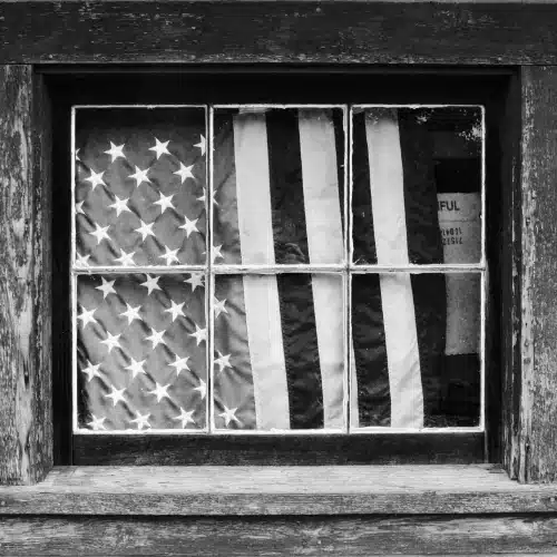 Amerikanische Flagge hinter einer Fensterscheibe als Sinnbild für Patriotismus, Ausgrenzung und gesellschaftliche Polarisierung in American History X.