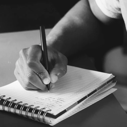 Hand schreibt mit einem Stift in ein Schulheft – Symbolbild zu Precious (2009)