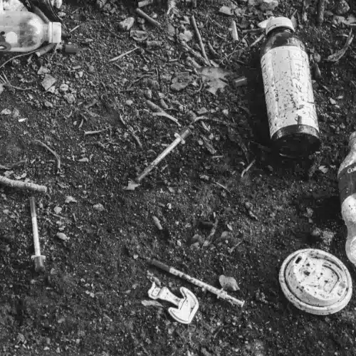 Spritzen und leere Flaschen auf dem Boden – Symbolbild für Drogenkonsum im Film „Trainspotting“ (1996).